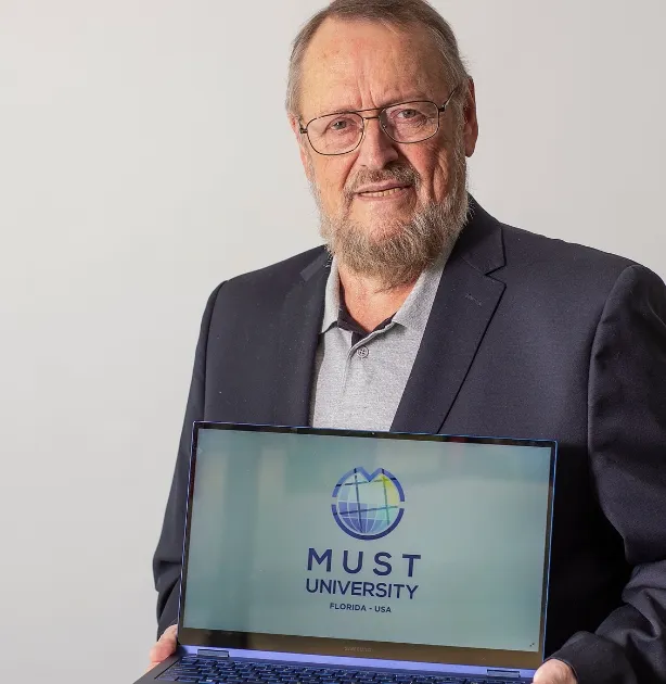 Homem de terno segurando um laptop que exibe o logotipo da MUST University Florida - USA.